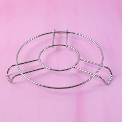 A silver wire hot pot stand is placed on a solid pink background.
