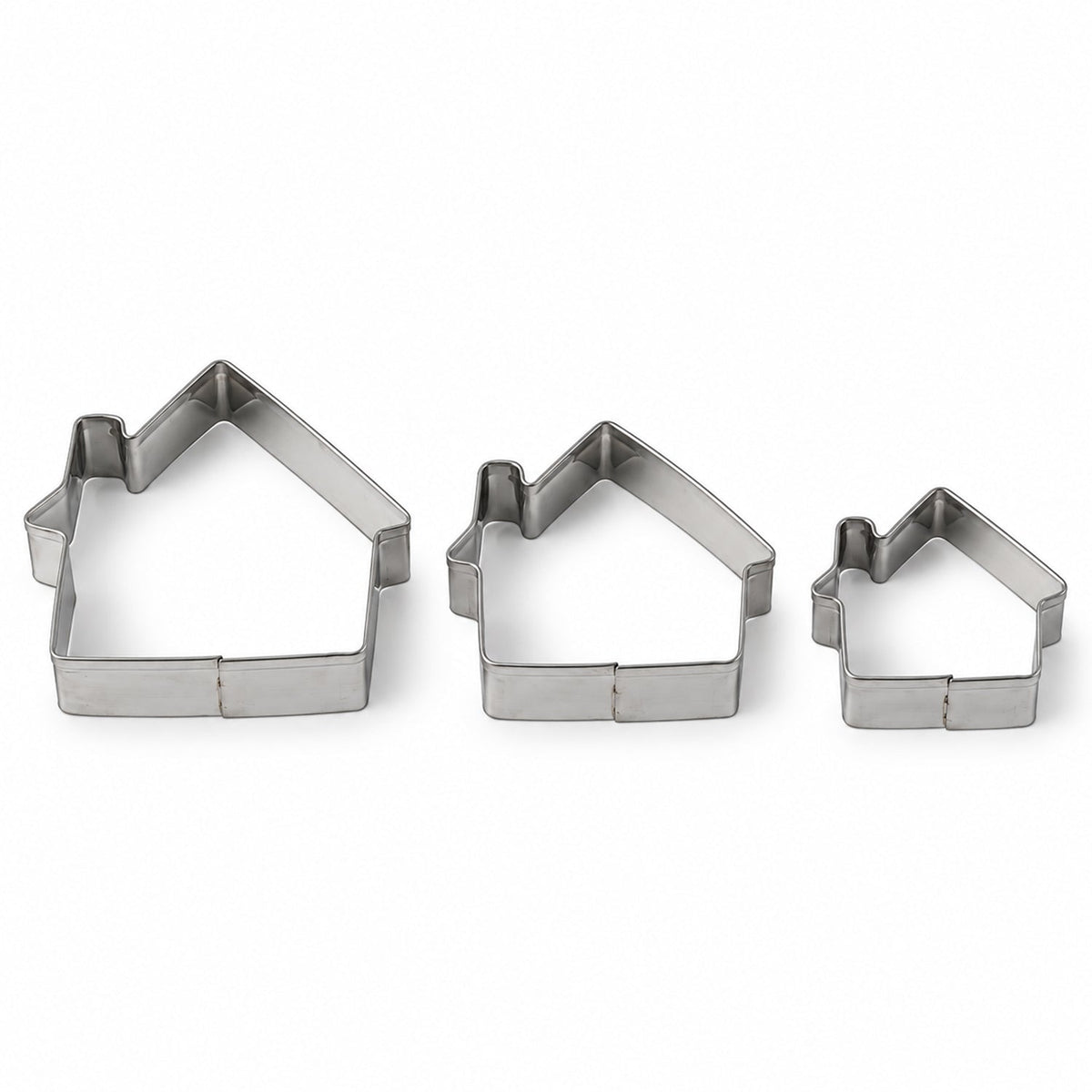 Three silver house-shaped cookie cutters of varying sizes arranged on a plain white background.