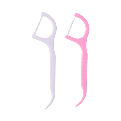 One white and one pink dental floss pick standing upright against a plain white background.