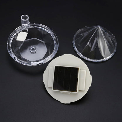 Disassembled clear plastic diamond light components, including a top, bottom, and a solar panel with a white base.