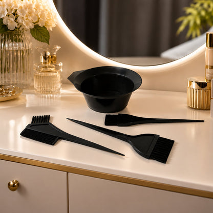 A black hair dye kit with a bowl and three brushes displayed on a white vanity table with a round mirror and perfume bottles.
