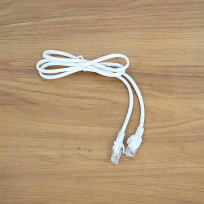 A coiled white ethernet cable with two clear plastic connectors is displayed on a wooden surface.