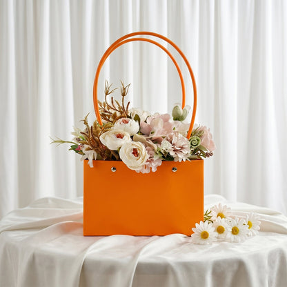 Orange flower gift bag filled with pink roses and artificial flowers for gifting