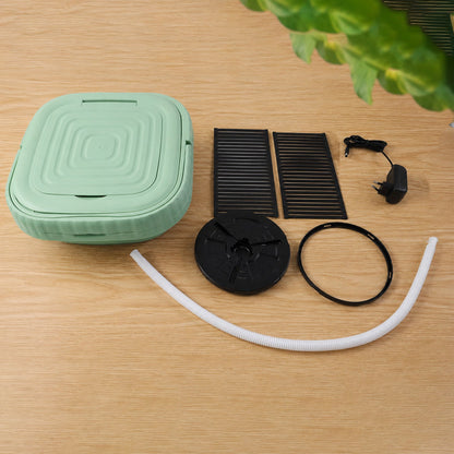 The green portable washing machine is shown collapsed with its lid closed, alongside various black accessories and – view 5