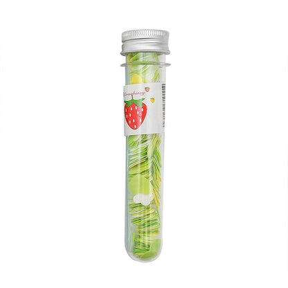 A clear tube with a silver cap and a strawberry label contains green and yellow flower-shaped paper soap strips.