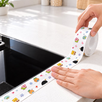 Two hands are applying the cartoon-printed sealing tape around the edge of a black cooktop on a white counter.
