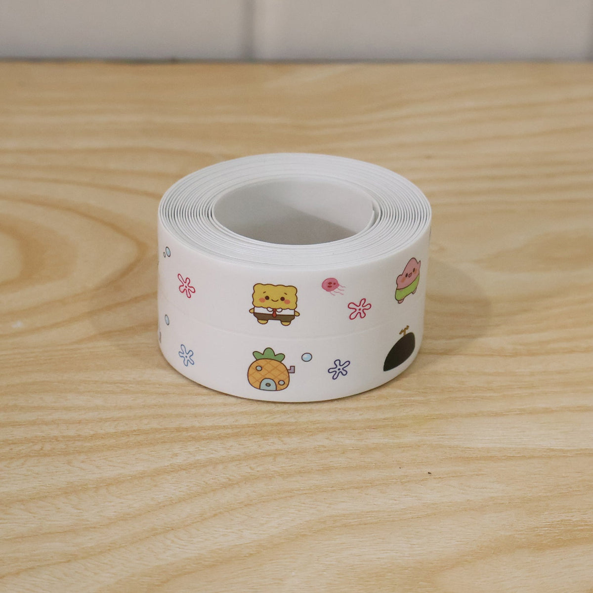 A single roll of white sealing tape with colorful cartoon characters rests on a light wooden surface.