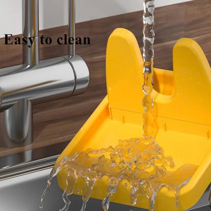 Water flowing from a silver faucet into a yellow plastic lid and spoon rest, demonstrating its easy-to-clean feature.