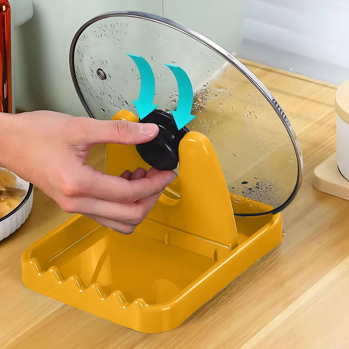A hand placing a black pot lid handle onto a yellow plastic lid and spoon rest, with blue arrows indicating placement.