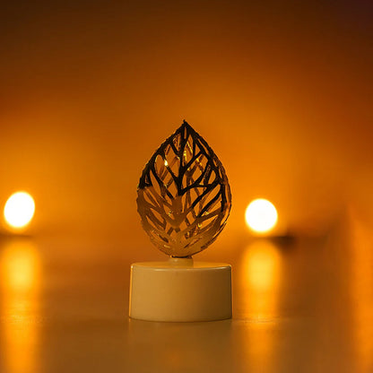 A single golden leaf LED candle glows brightly in a close-up shot against a blurred, warm-toned background.