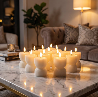 Twelve cream ribbed flameless candles with bright wicks illuminate a marble table in a cozy living room.