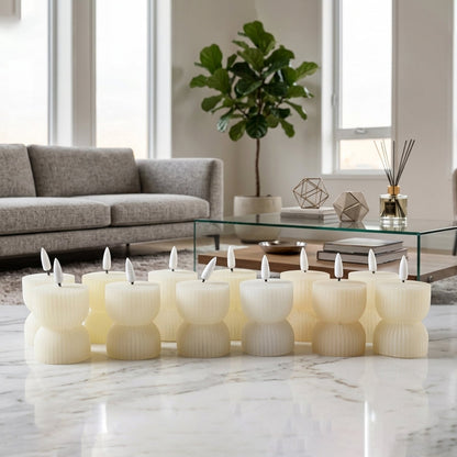 Twelve cream ribbed flameless candles with lit wicks are displayed on a white marble floor in a bright living space.