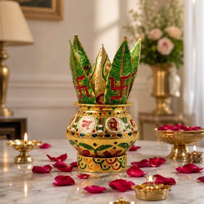 A golden metal Kalash with green leaves, surrounded by red rose petals and lamps.