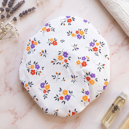Floral patterned food cover on a marble surface with lavender sprigs and small oil bottle.