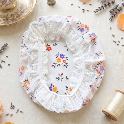 Underside of the elasticated food cover, revealing ruffled edges and floral pattern on a white cloth.