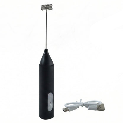A black handheld electric milk frother with a double whisk head stands next to a coiled white USB charging cable on a white