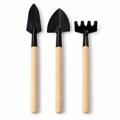 Three small gardening tools, including two trowels and a rake, stand upright on a plain white background.