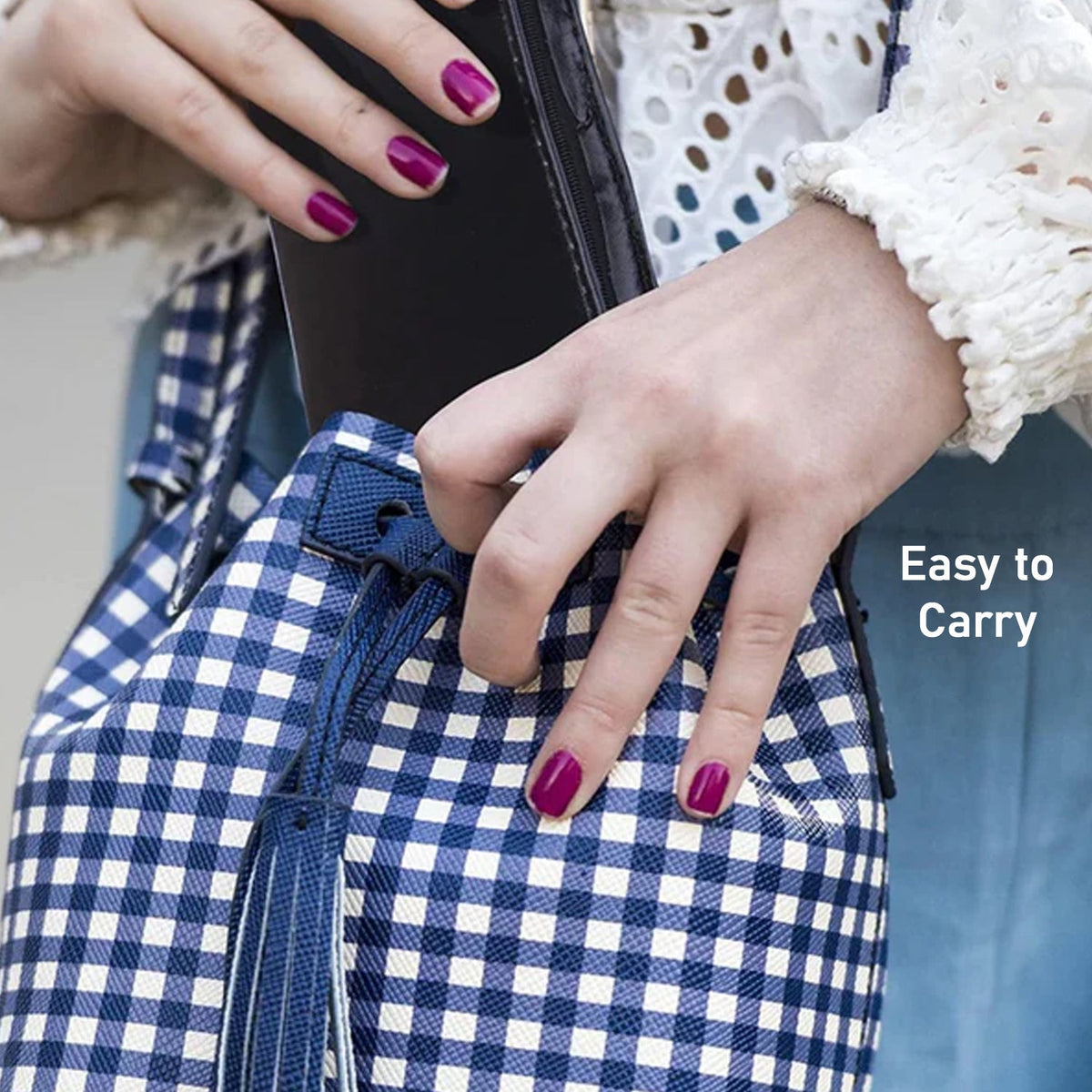 A person with purple nail polish places a black item into a blue and white checkered bag with a tassel, labeled 'Easy to