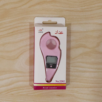 The pink digital beads counter packaged in a white and pink box with Arabic text, on a light wooden background.