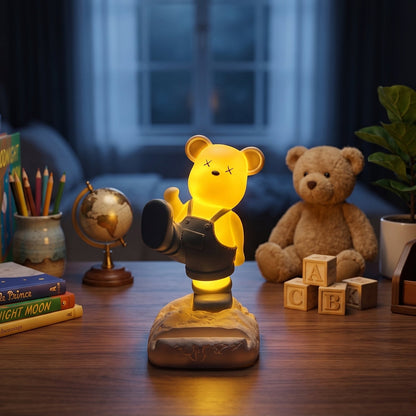 A glowing yellow bear phone holder with dark overalls on a desk at night, surrounded by toys.