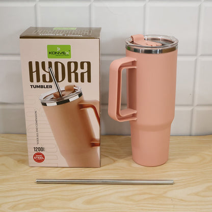 A pink tumbler with its packaging box and a metal straw are displayed on a wooden surface.