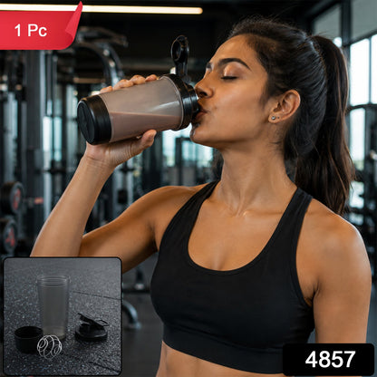 A woman in a black sports bra drinks from a grey and black shaker bottle in a gym, with a red "1 Pc" label and a black