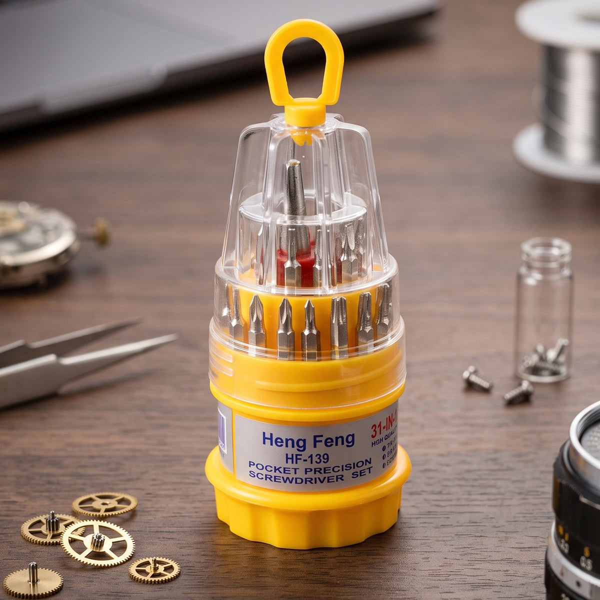 A yellow and clear pocket precision screwdriver set with various bits is displayed on a wooden table with small gears and
