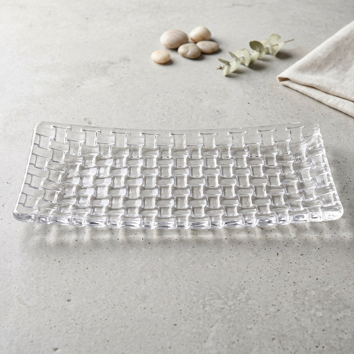 Rectangular clear glass serving platter with a textured basketweave design on a light gray surface.
