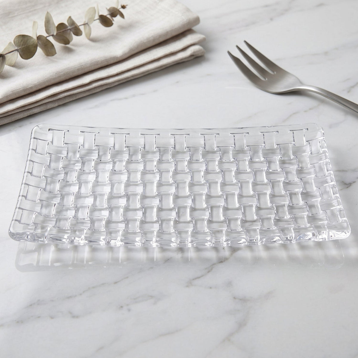 Rectangular clear glass tray featuring a basketweave texture, placed on a white marble countertop with a fork.