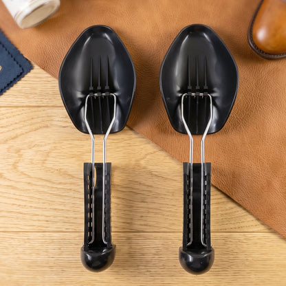 Two black plastic shoe supports with metal springs, on a wooden surface with a brown leather mat.