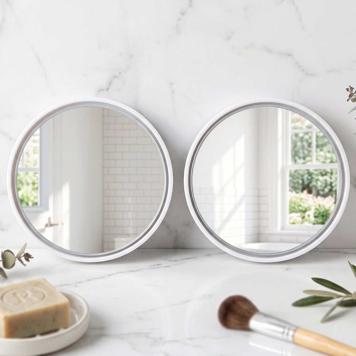 Two round white-framed mirrors on a white marble counter with soap and a makeup brush.