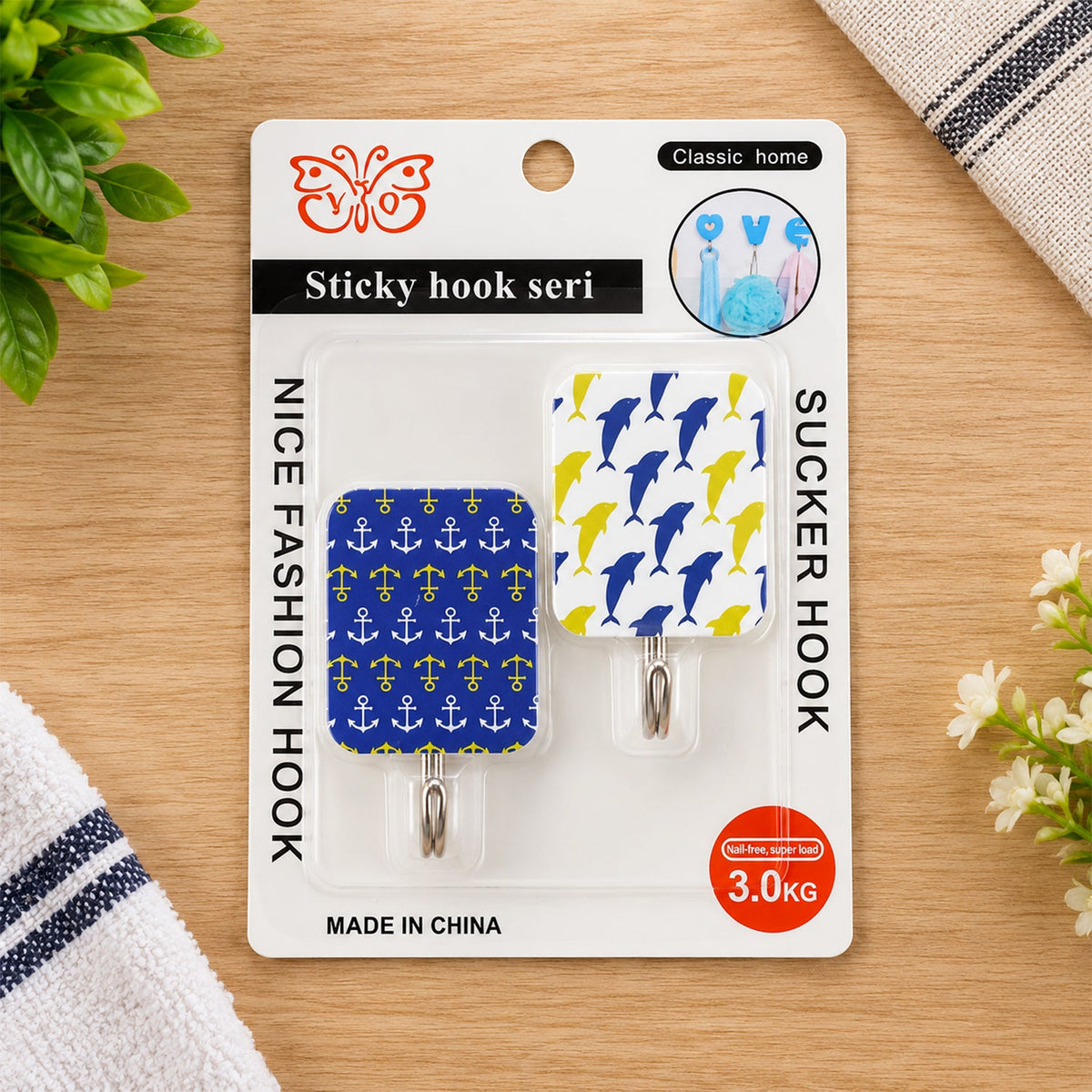 Two patterned adhesive hooks on retail packaging, one with blue dolphins, the other with yellow anchors.