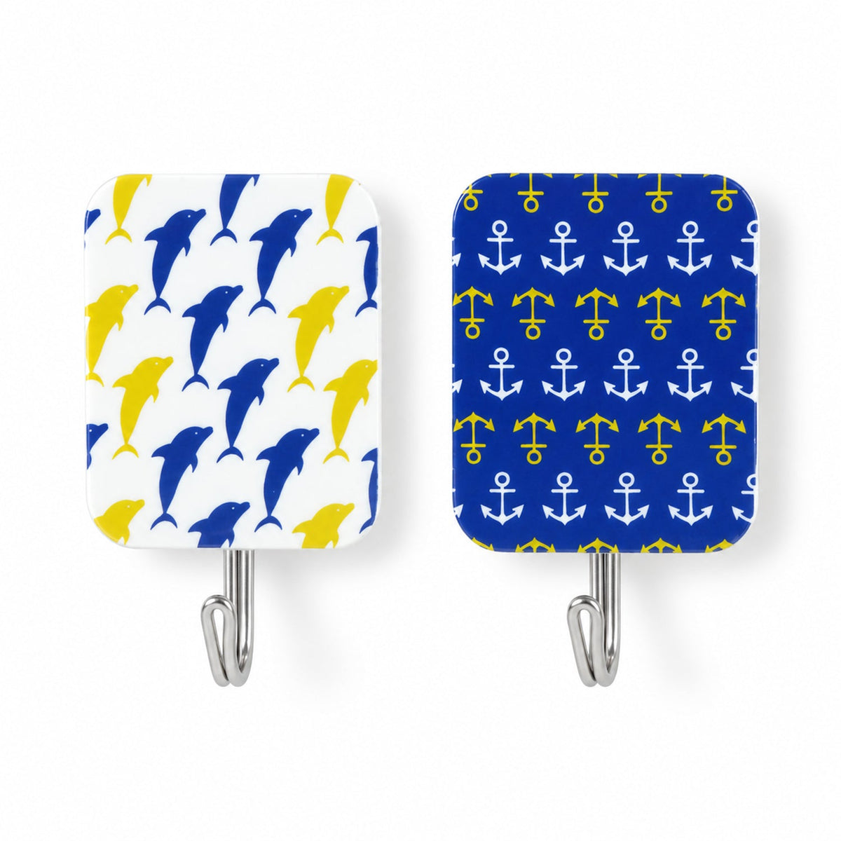 Two rectangular adhesive hooks, one with a blue dolphin pattern and the other with yellow anchors, on a white surface.