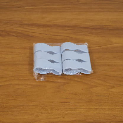 Four blue plastic towel clips, shaped like bowties, packaged in clear plastic on a wooden surface.