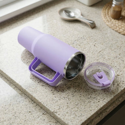 A purple insulated tumbler with its lid removed, showing the stainless steel interior, on a speckled countertop.