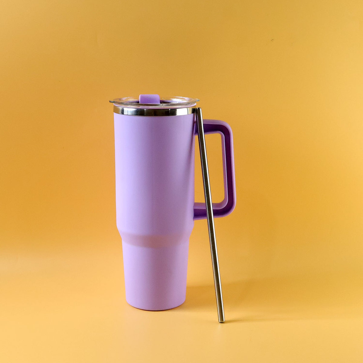 A purple insulated tumbler with a handle, lid, and a metal straw standing upright on an orange background.