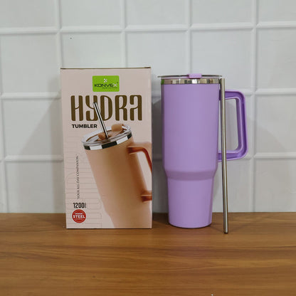 A purple insulated tumbler with a handle and straw stands next to its product box on a wooden surface.