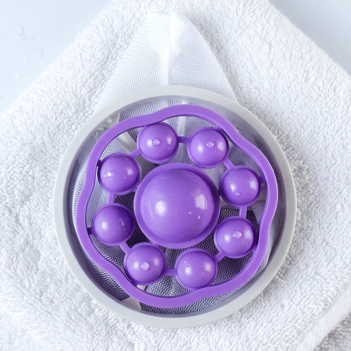 The top view of a purple and white floating lint mesh bag resting on a white towel.