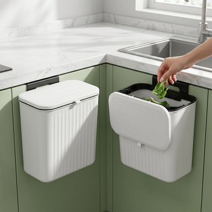 Two white ribbed compost bins, one closed and one open, are mounted on green kitchen cabinets next to a sink.