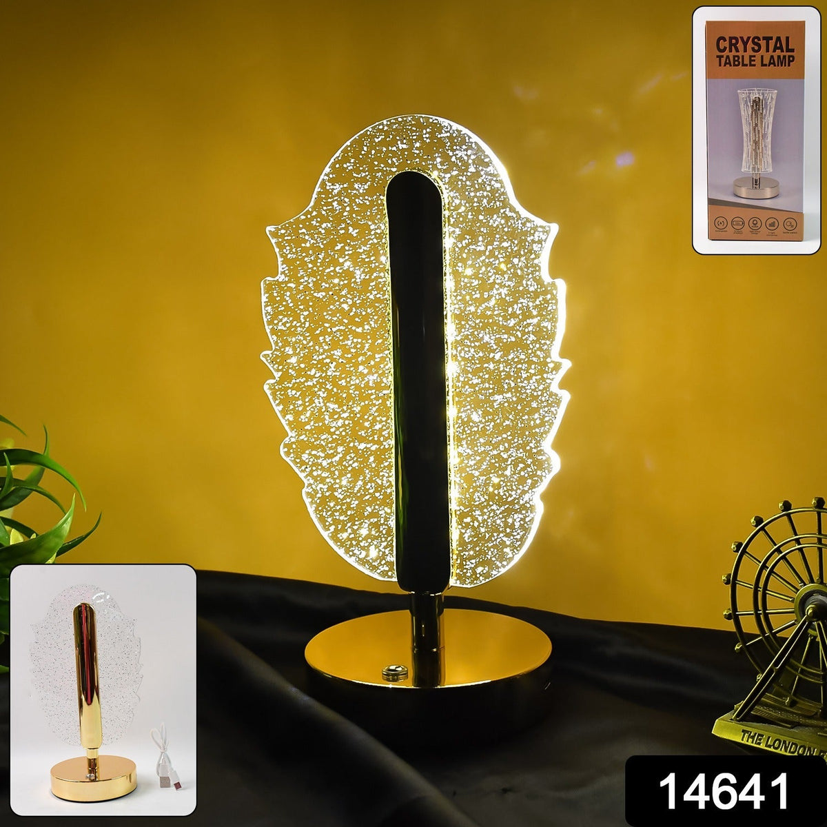 A glowing feather-shaped crystal table lamp with a gold base, a small inset, and a product code on a dark surface.