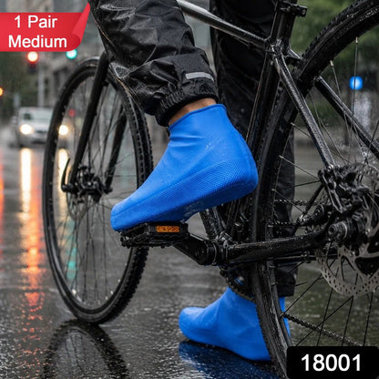 A person on a bicycle wears blue waterproof shoe covers on a wet city street, with a red "1 Pair Medium" label.