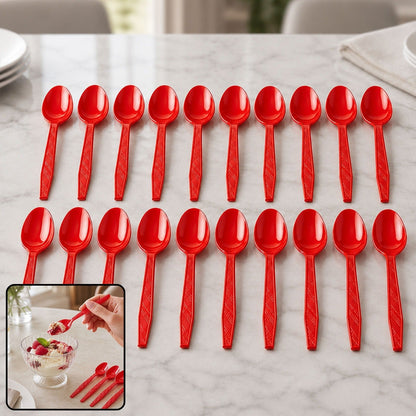 Twenty red plastic spoons arranged in two rows on a white marble table with plates in the background.