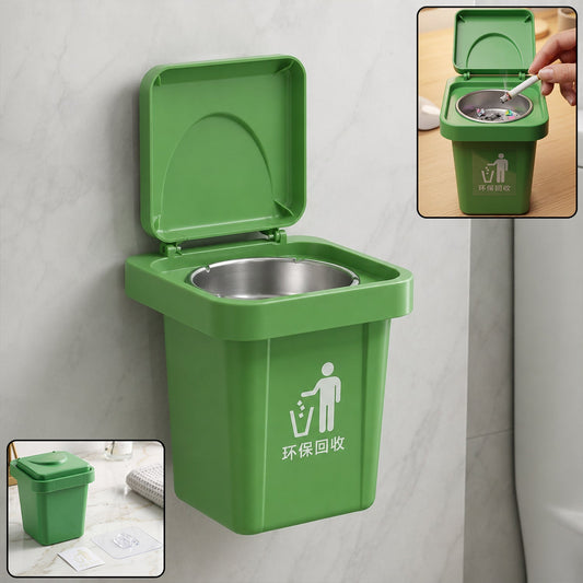 A wall-mounted green mini trash can ashtray with an open lid and a small inset image of a hand holding a cigarette over it.