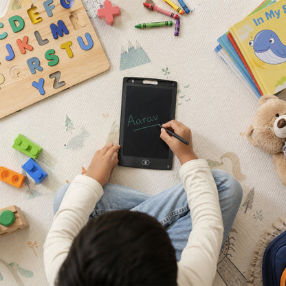 A child sits on a patterned mat, writing "Aarav" on a black LCD tablet, with alphabet puzzles and crayons visible nearby.