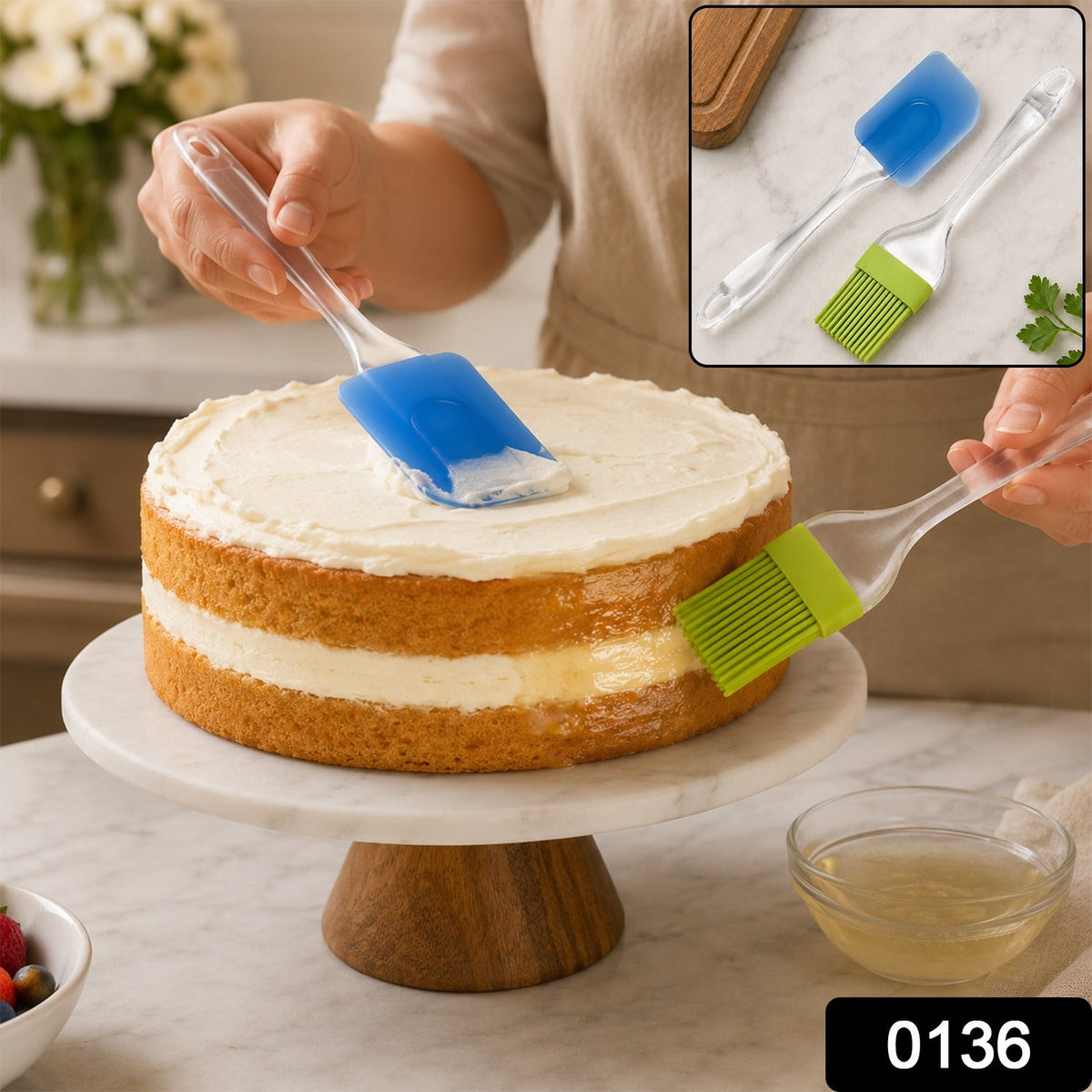 A person uses a blue silicone spatula to frost a two-layer cake and a green silicone brush to glaze the side.