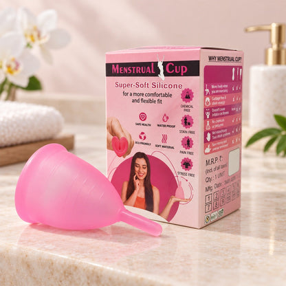 A pink silicone menstrual cup rests beside its pink and white product box on a bathroom counter with orchids.