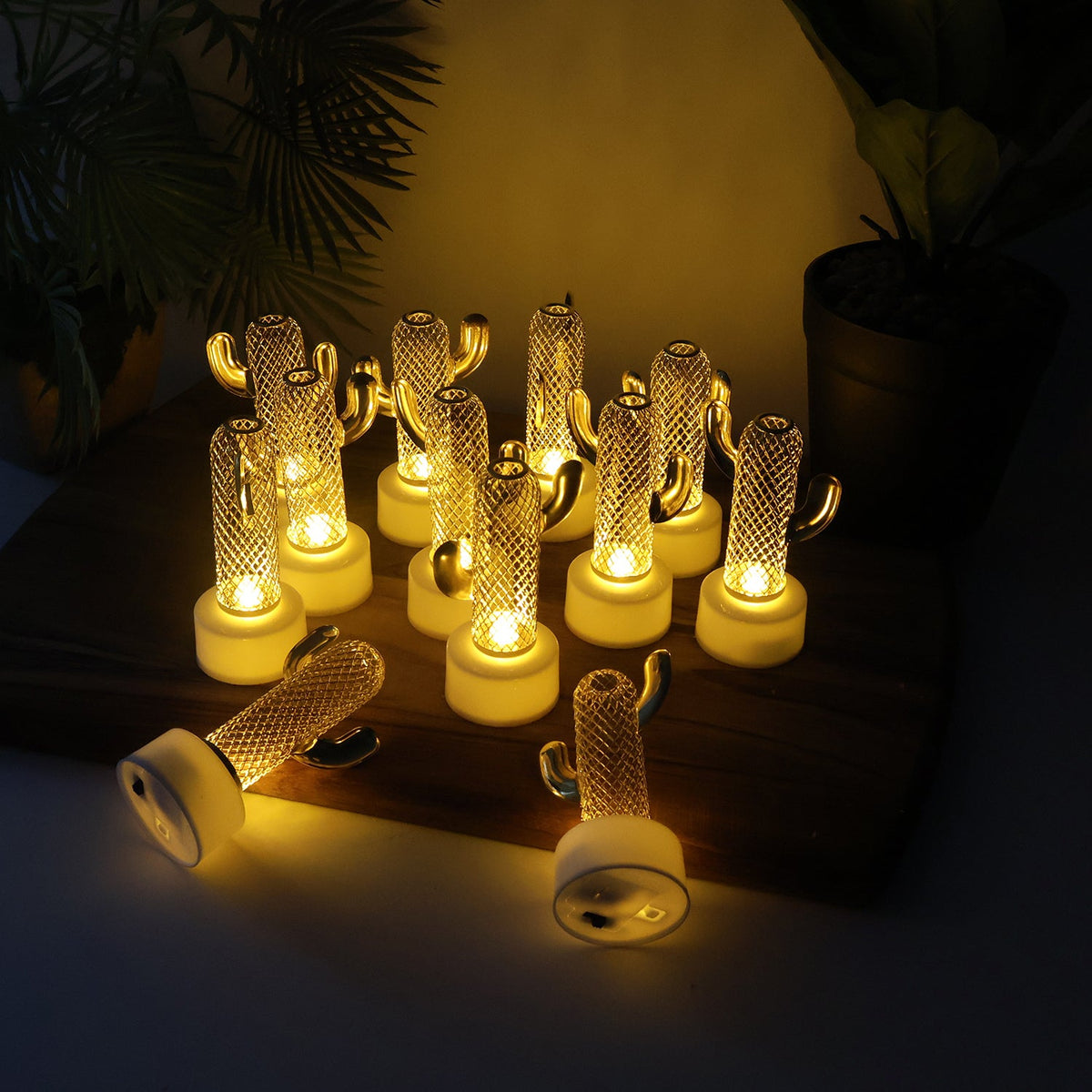 Ten glowing cactus-shaped LED lights on a wooden board, with two more lying on their sides in the foreground.