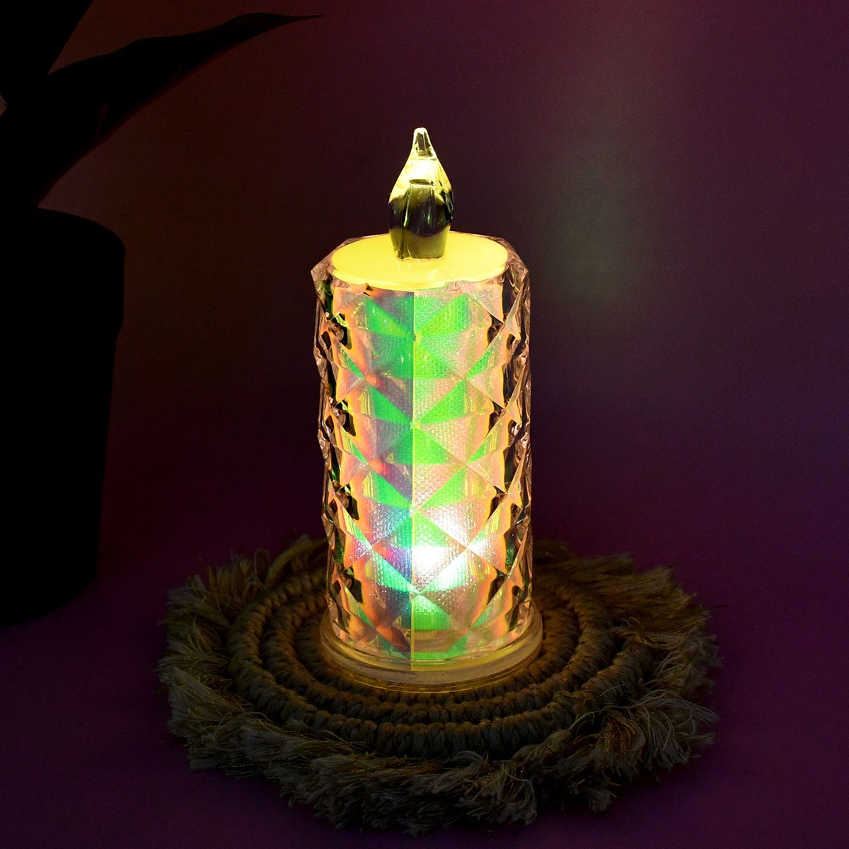 A single iridescent LED candle with a textured surface glows with a multicolored light, resting on a woven mat.