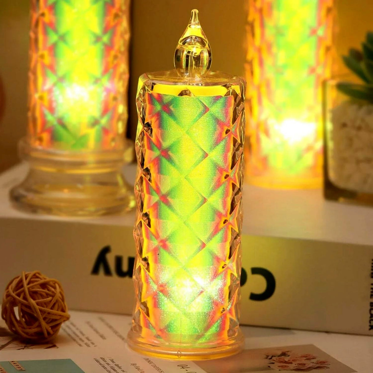 A close-up of a single iridescent LED candle with a textured surface, glowing with a vibrant green and yellow light.