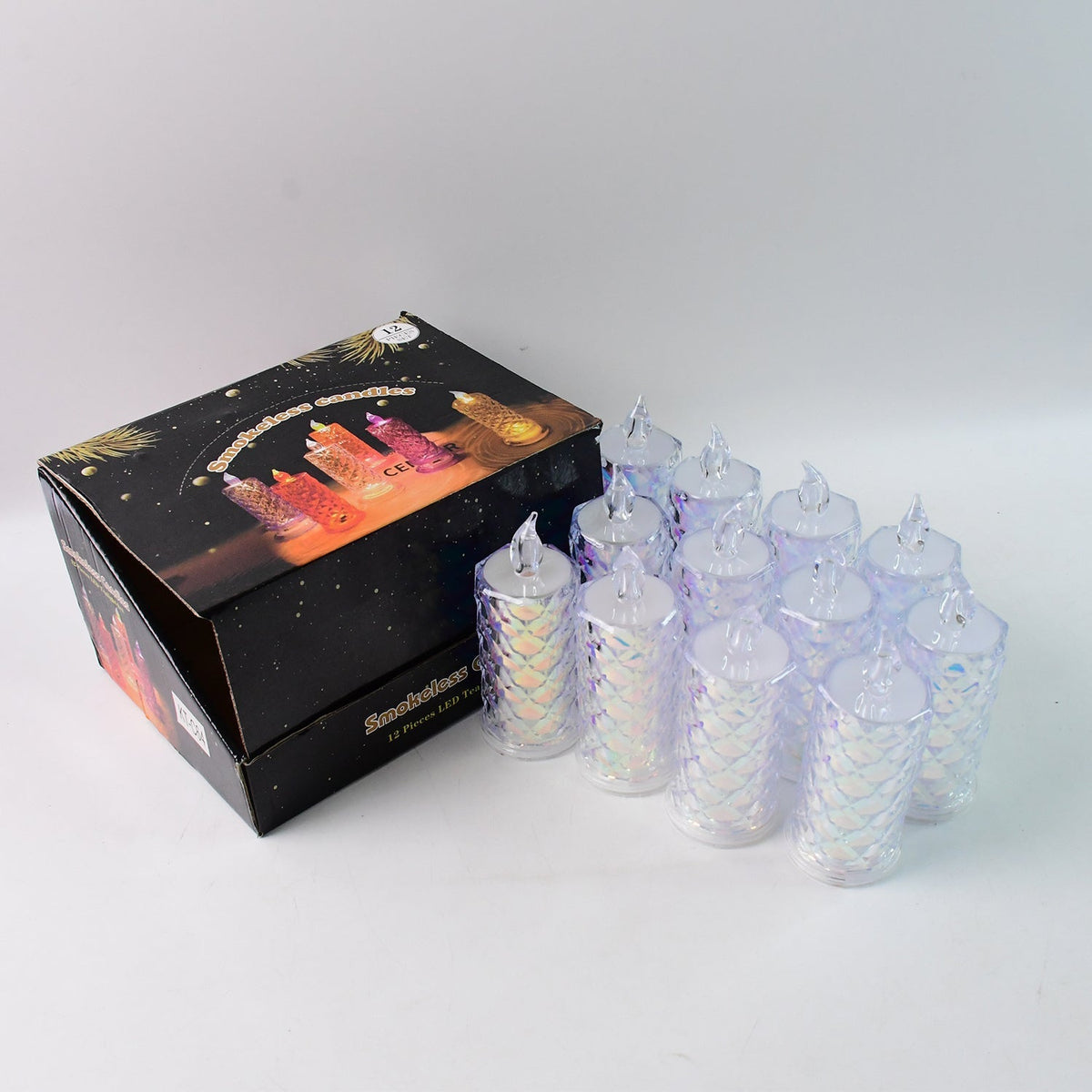 Twelve iridescent LED candles with textured surfaces are arranged next to an open black product box on a white surface.